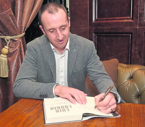 Eoin Larkin signing a copy of his book Camouflage