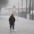 A person walking through floodwater on a pavement